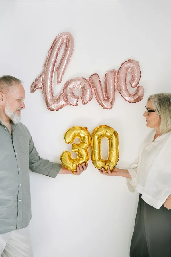 A couple celebrating their anniversary with love and milestone balloons